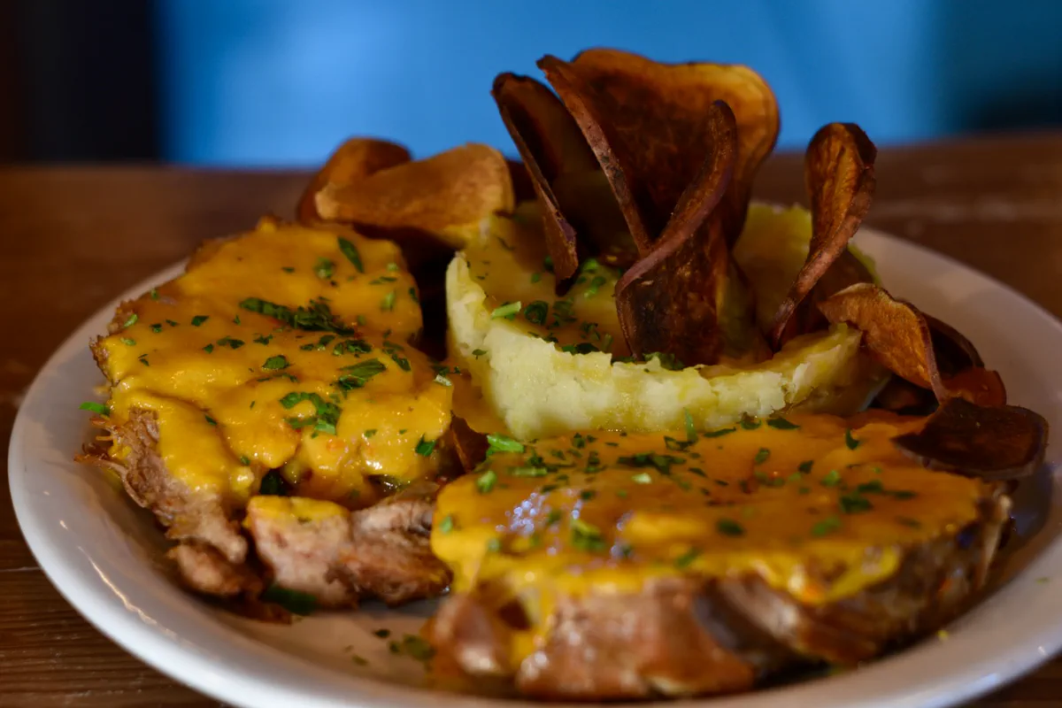 Corte de carne con salsa de queso, puré y chips de batata