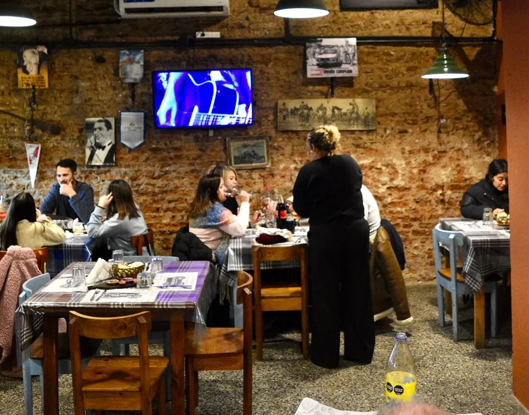 Salón del Bodegón Tras Cartón lleno de gente, con paredes de ladrillo y cuadros